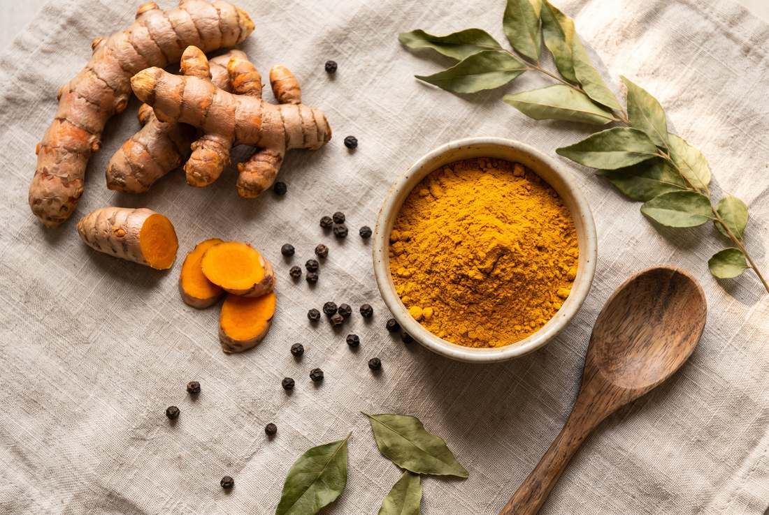 Overhead flat lay of fresh turmeric root and golden turmeric powder with black peppercorns on natural linen