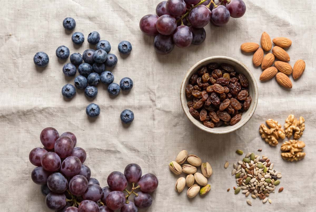 Overhead flat lay of blueberries, grapes, raisins, almonds and mixed seeds on a linen cloth